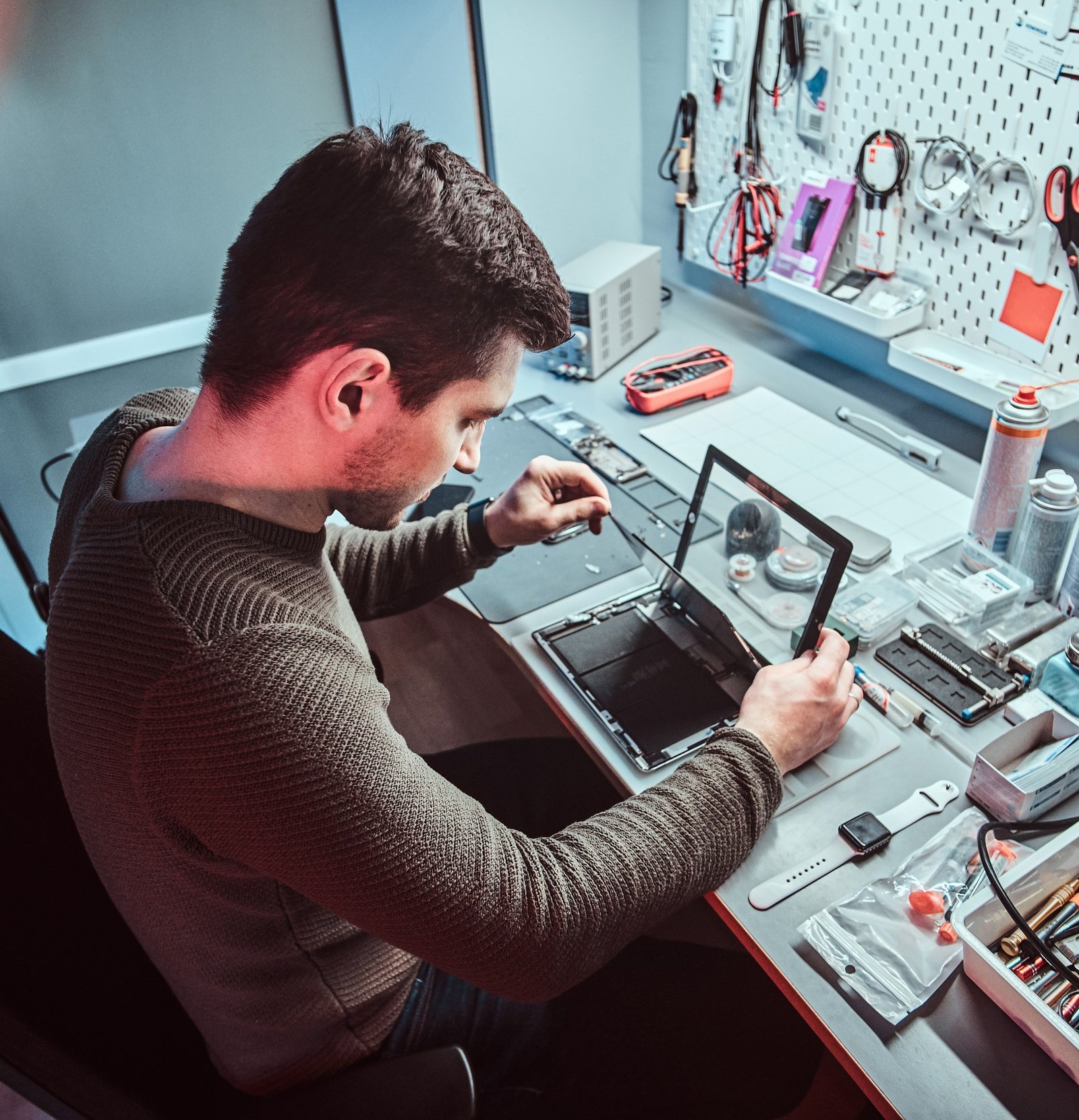 The technician repairs a broken tablet computer in a repair shop